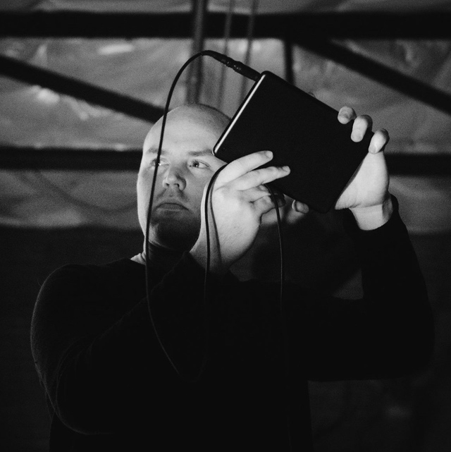 DMA faculty memeber Andrew Blanton working with a device in an underlit enviornment.